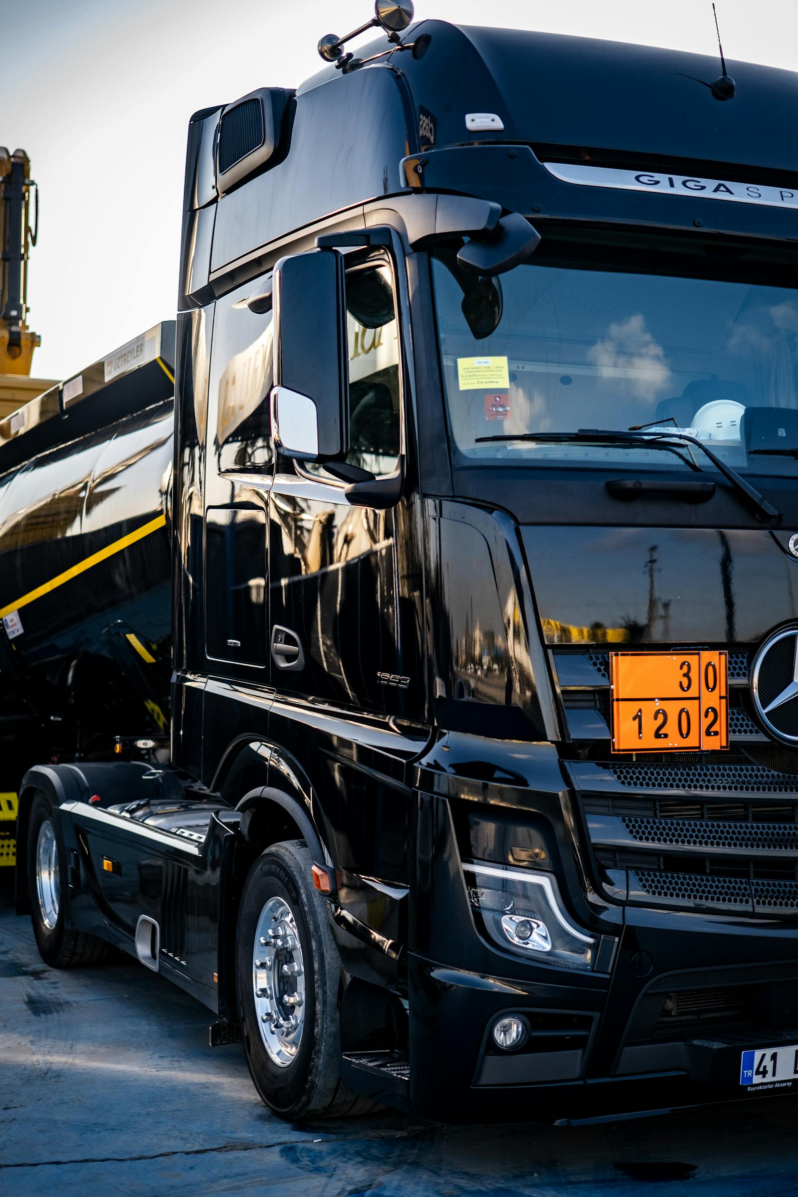 Black Mercedes tractor pulling a tanker on the road