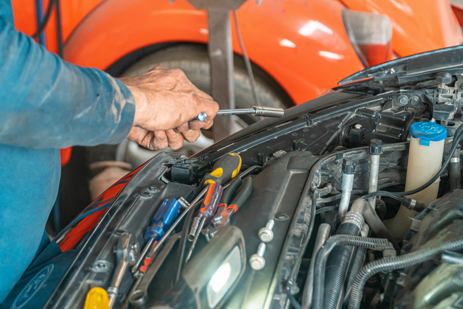 Car mechanic holding a hand tool, looking at the camera in a shop