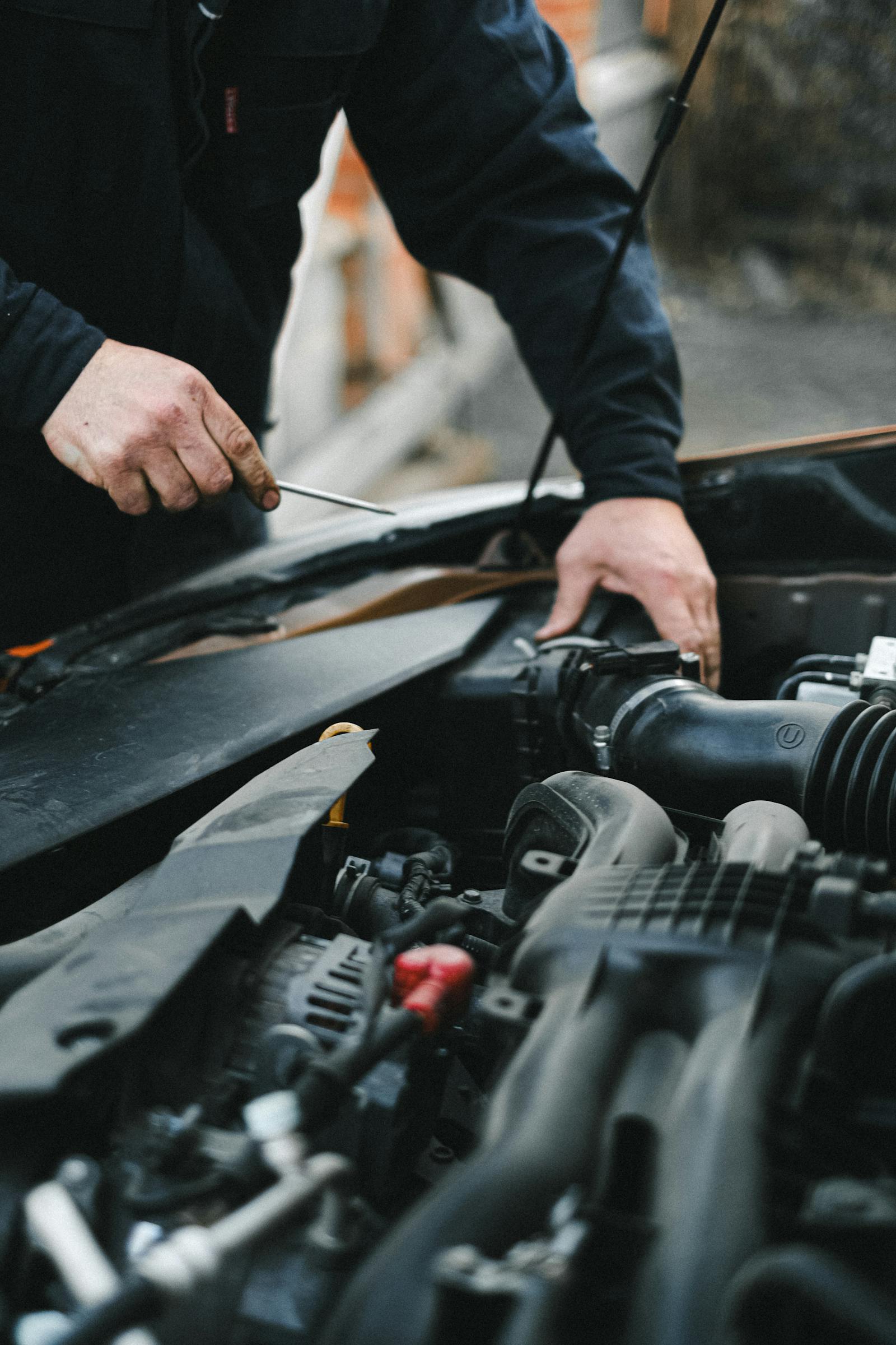 Two hands working on a car engine bay