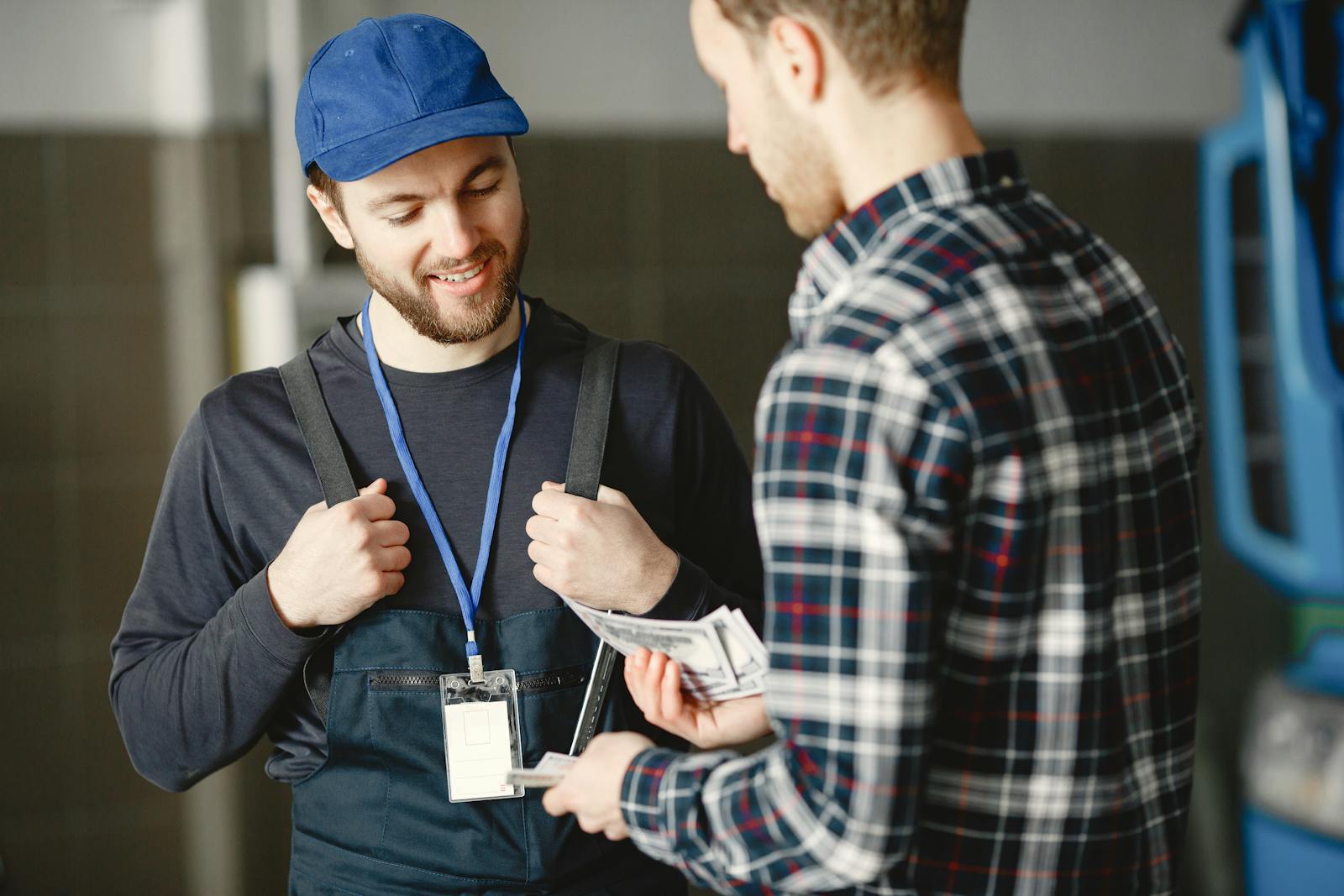 Mechanic accepting a cash payment from a customer in a shop