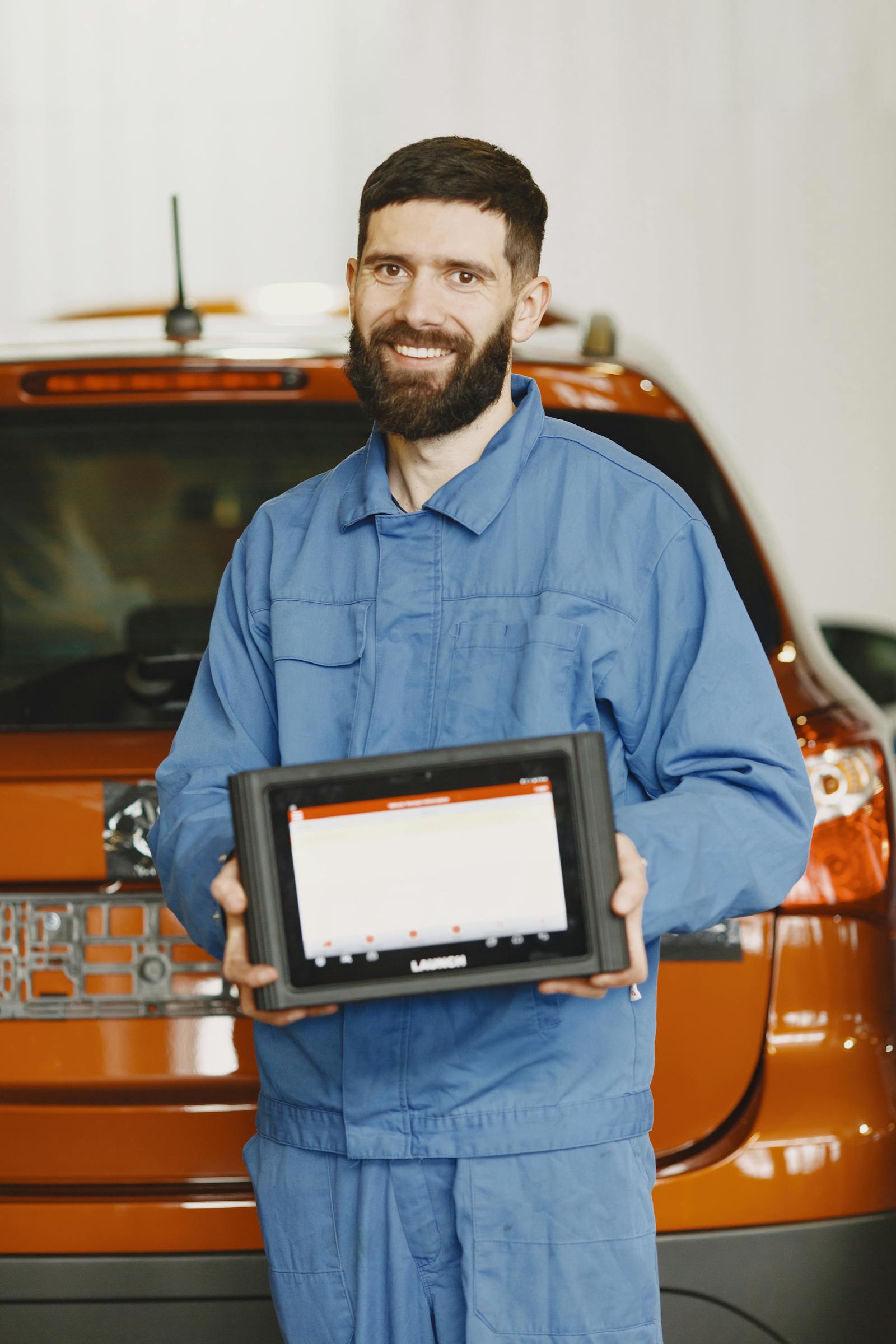 Mechanic using a tablet in a shop, taking notes on a vehicle