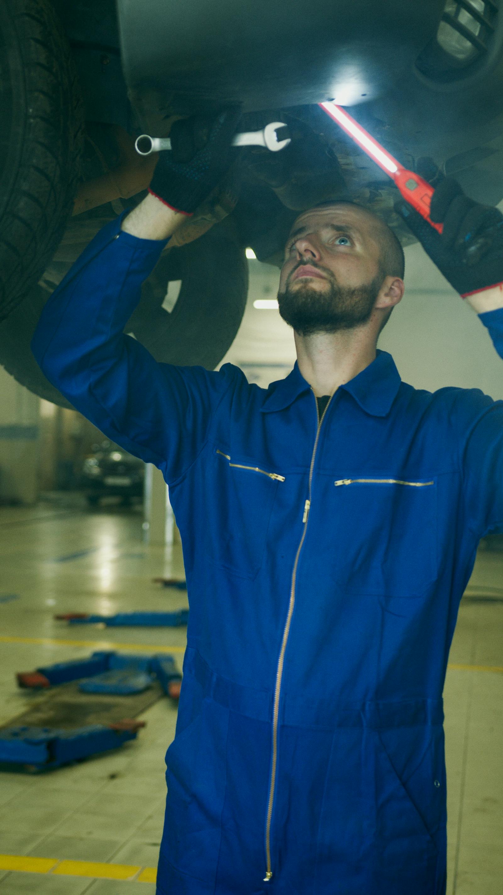Mechanic in coveralls working under a lifted car