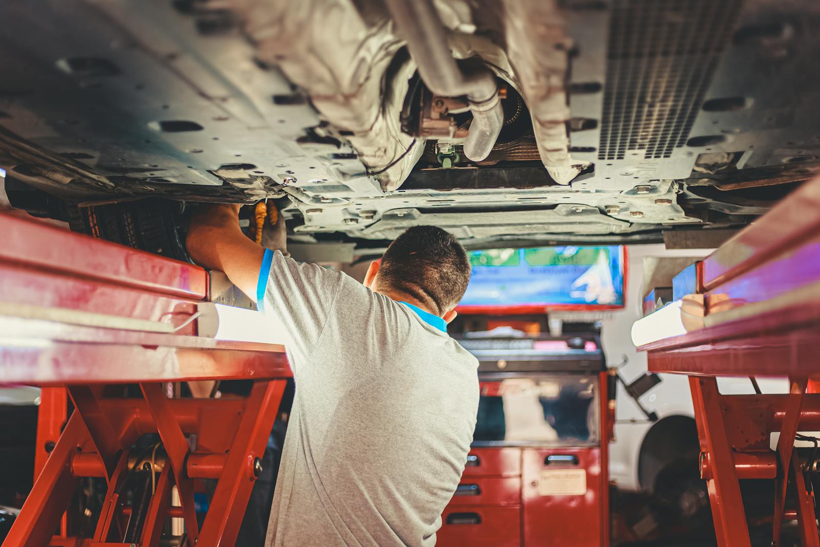 View of a mechanic standing beneath a vehicle on a hoist