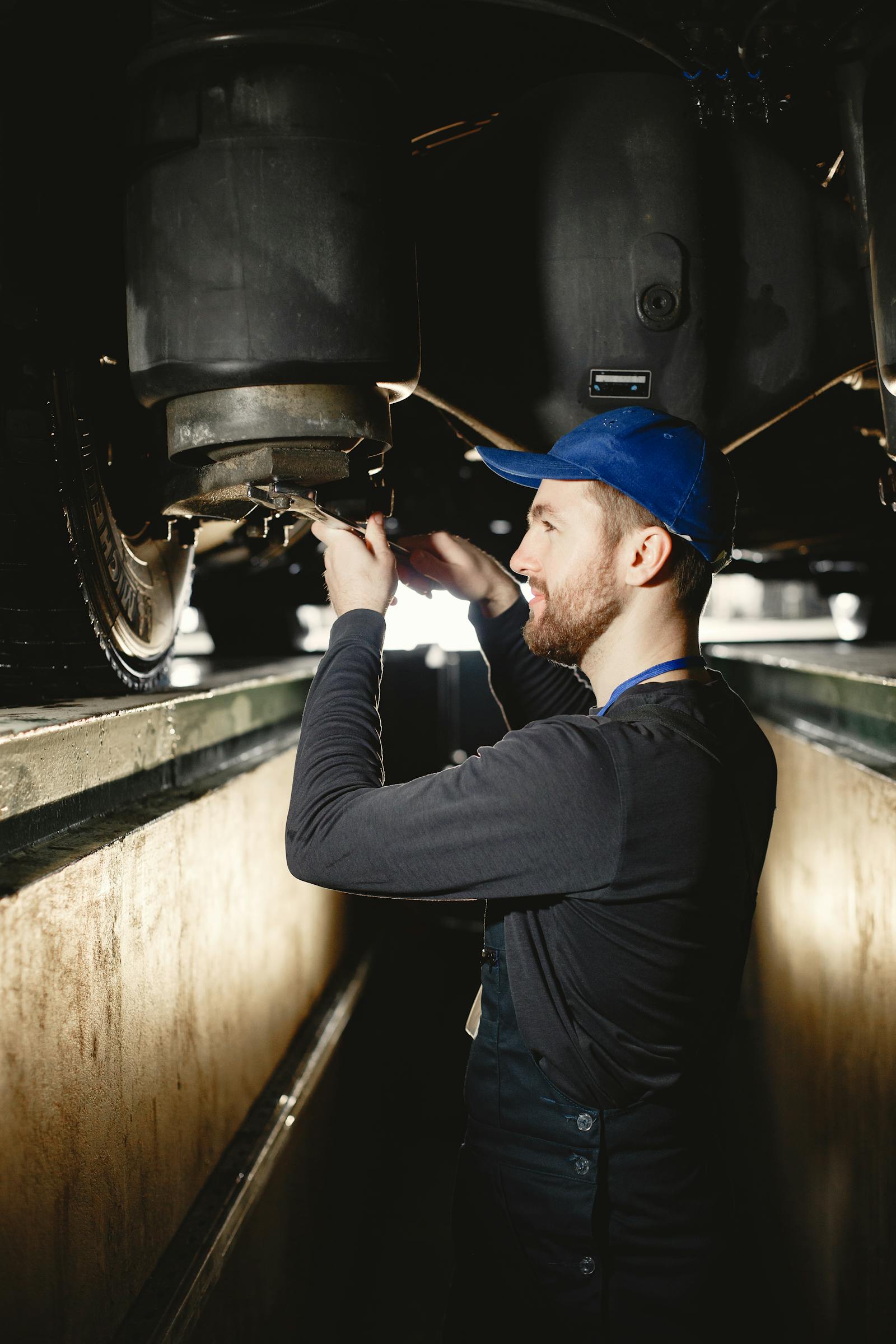Mechanic with a flashlight inspecting a vehicle's underbody