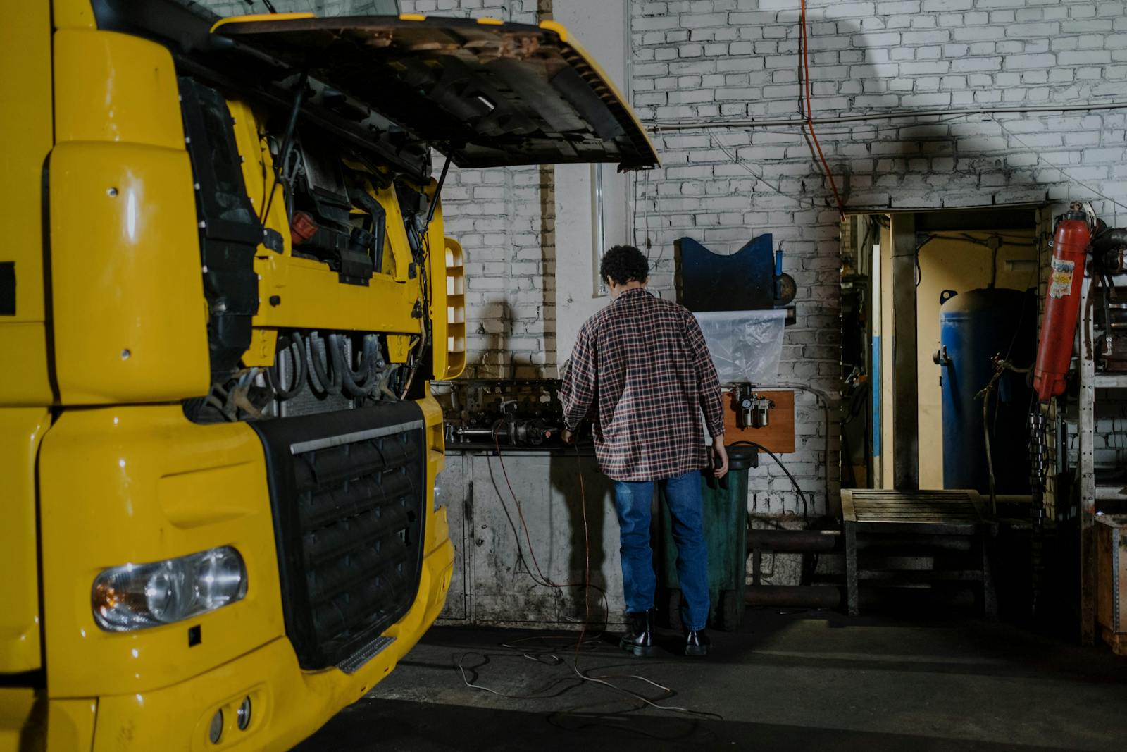 Mechanic working on a yellow heavy-duty truck engine