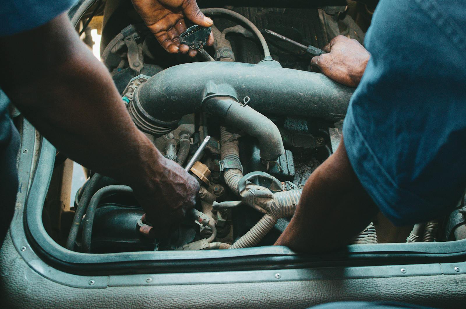 Two mechanics collaborating over an engine in a workshop