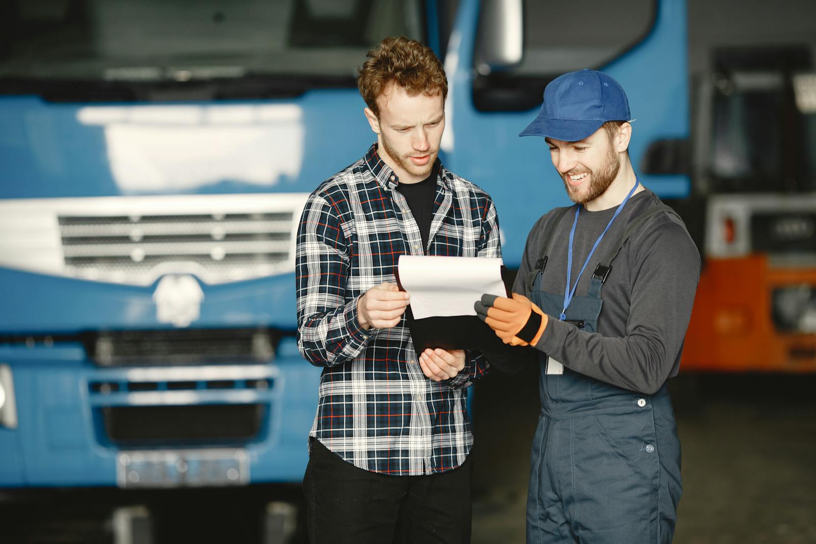 Two men reviewing a service document in front of a blue commercial truck