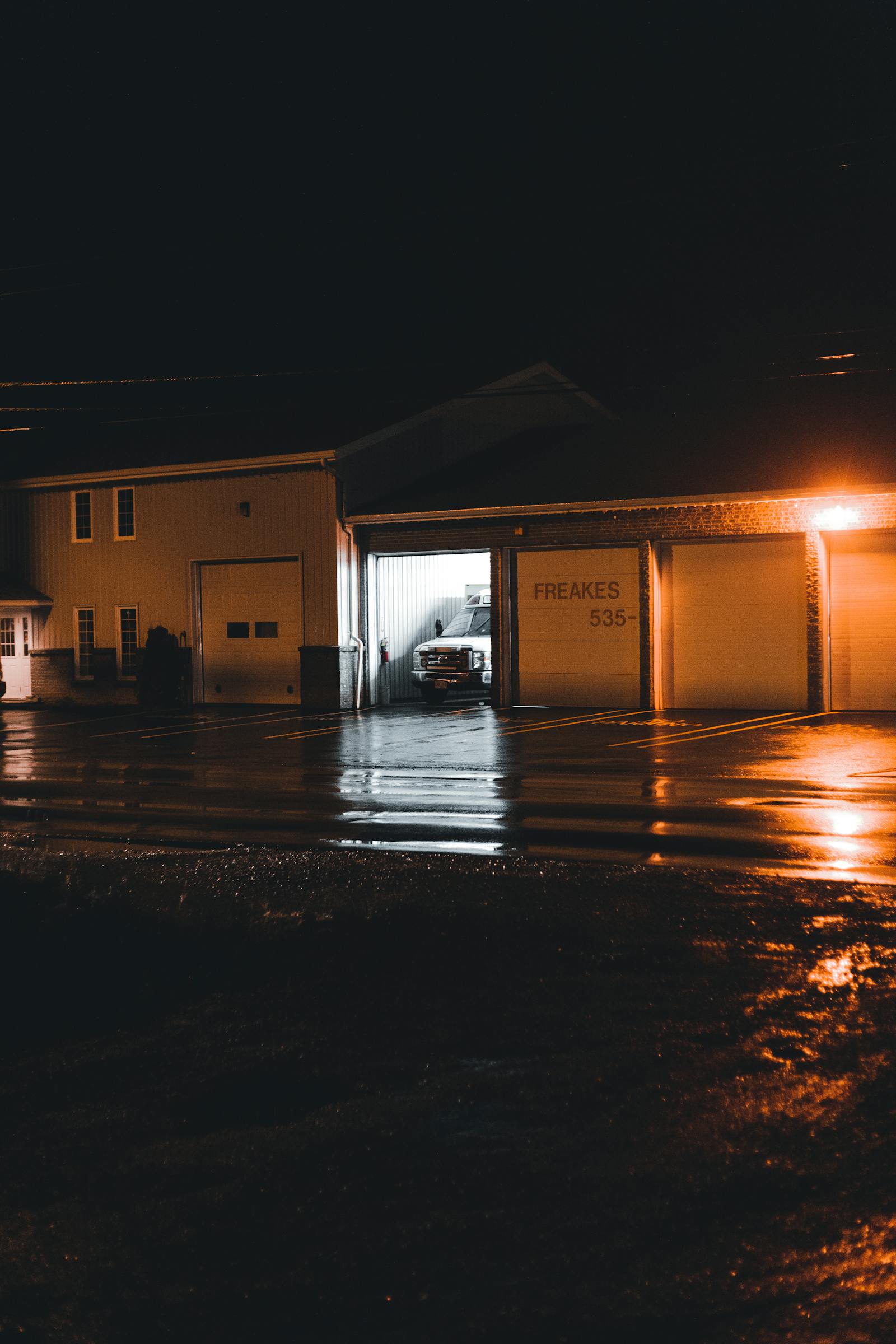 Service van parked outside a moody garage at night with warm interior lights