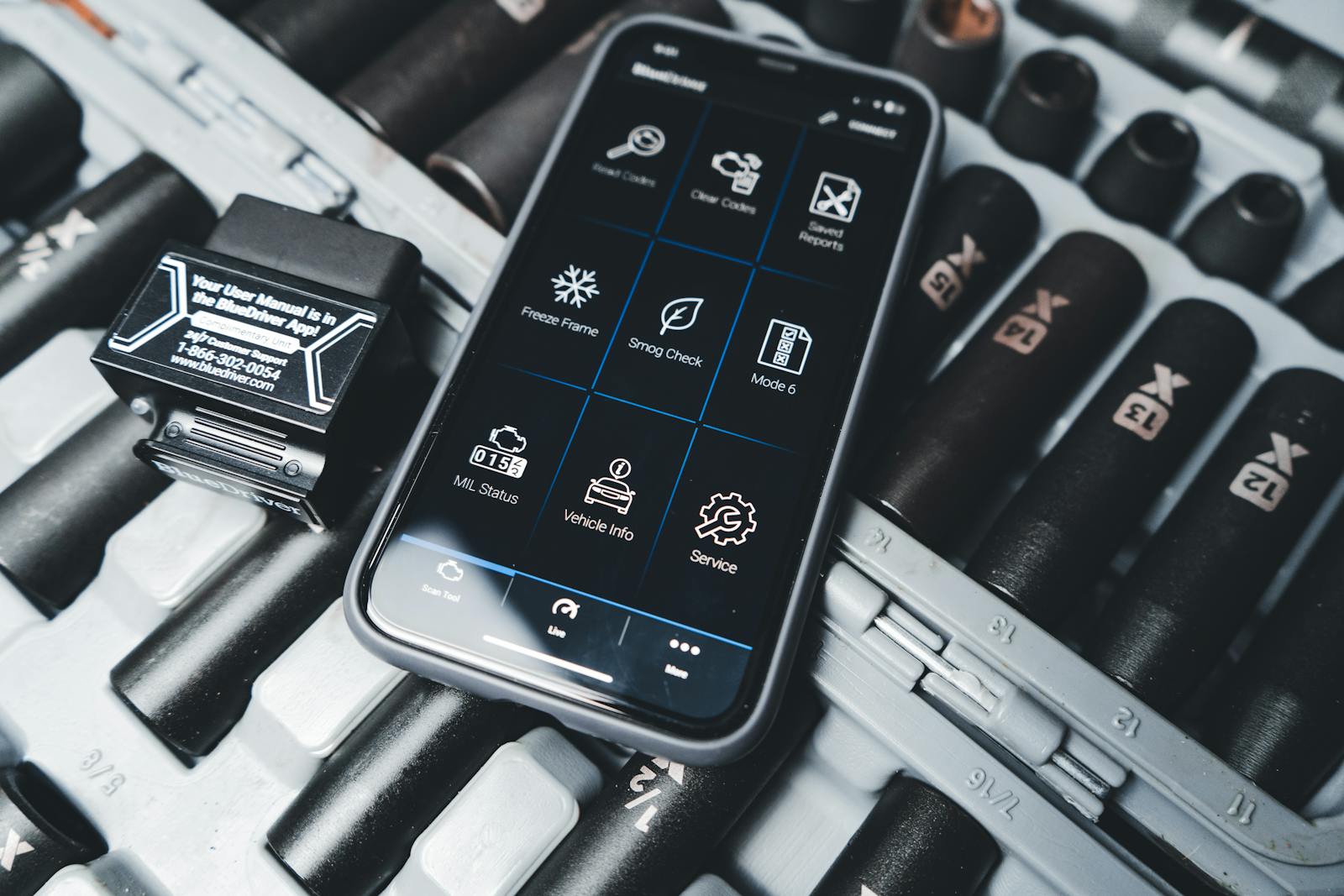 Smartphone running a vehicle diagnostic app next to a service tool