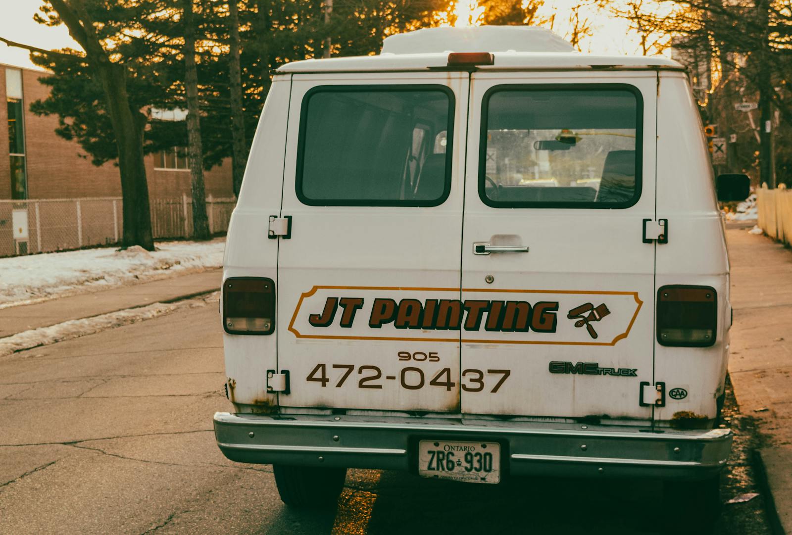 Branded GMC service van parked on a snowy street, signage visible on the side