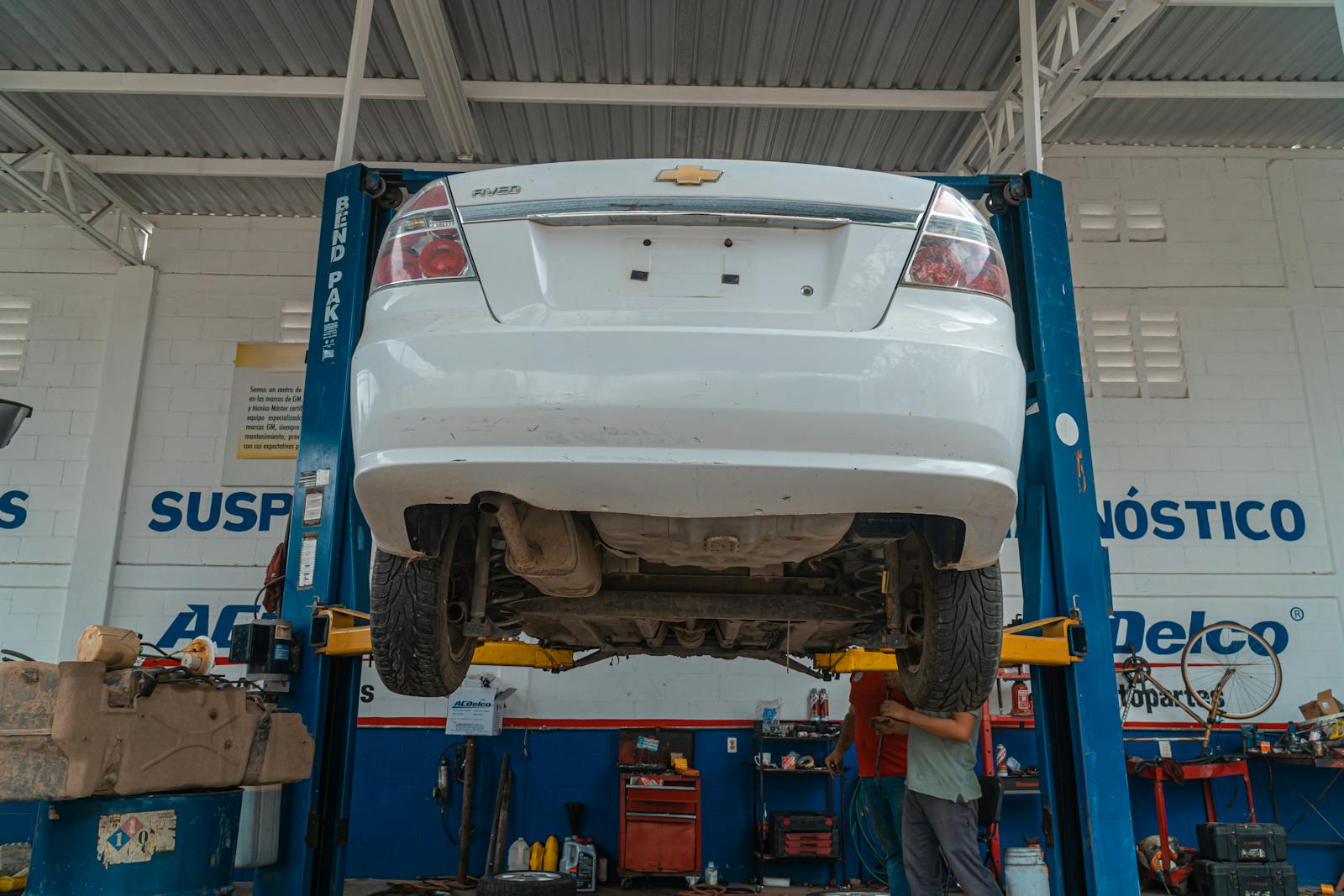 White car lifted on a shop hoist for under-vehicle service