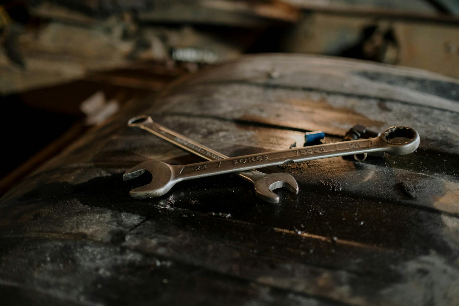 Two wrenches crossed on a weathered workshop surface